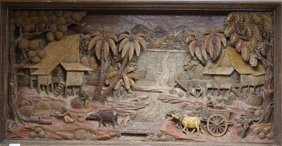 A large Thai hand-carved wood three dimensional picture, depicting farmers in a landscape 27in. x 52.5in.